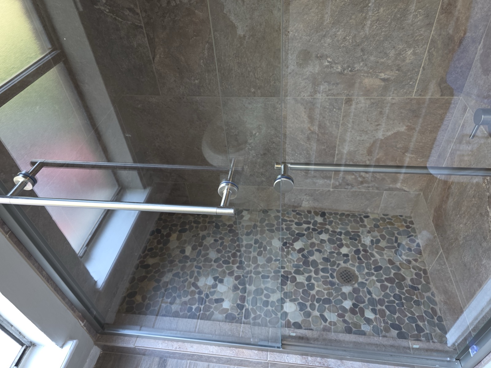 Wide slate shower with a pebble floor and a glass panel