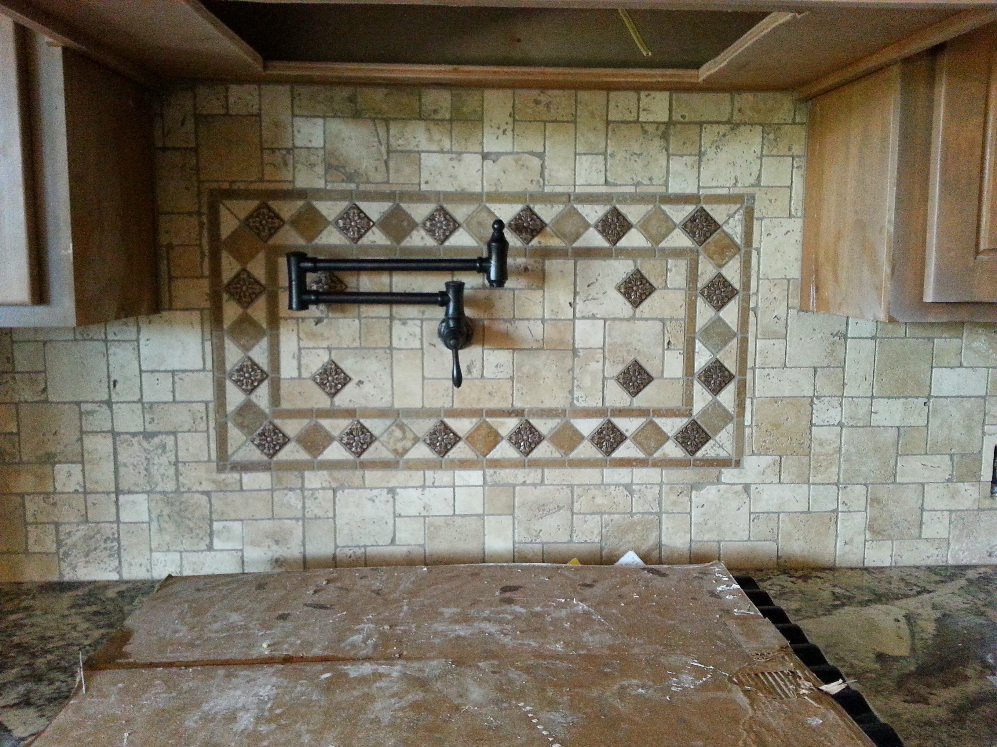 Kitchen with travertine tile medallion and pot filler over the range