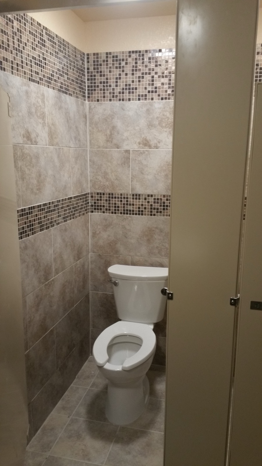 Commercial restroom stall with tile and mosaic band